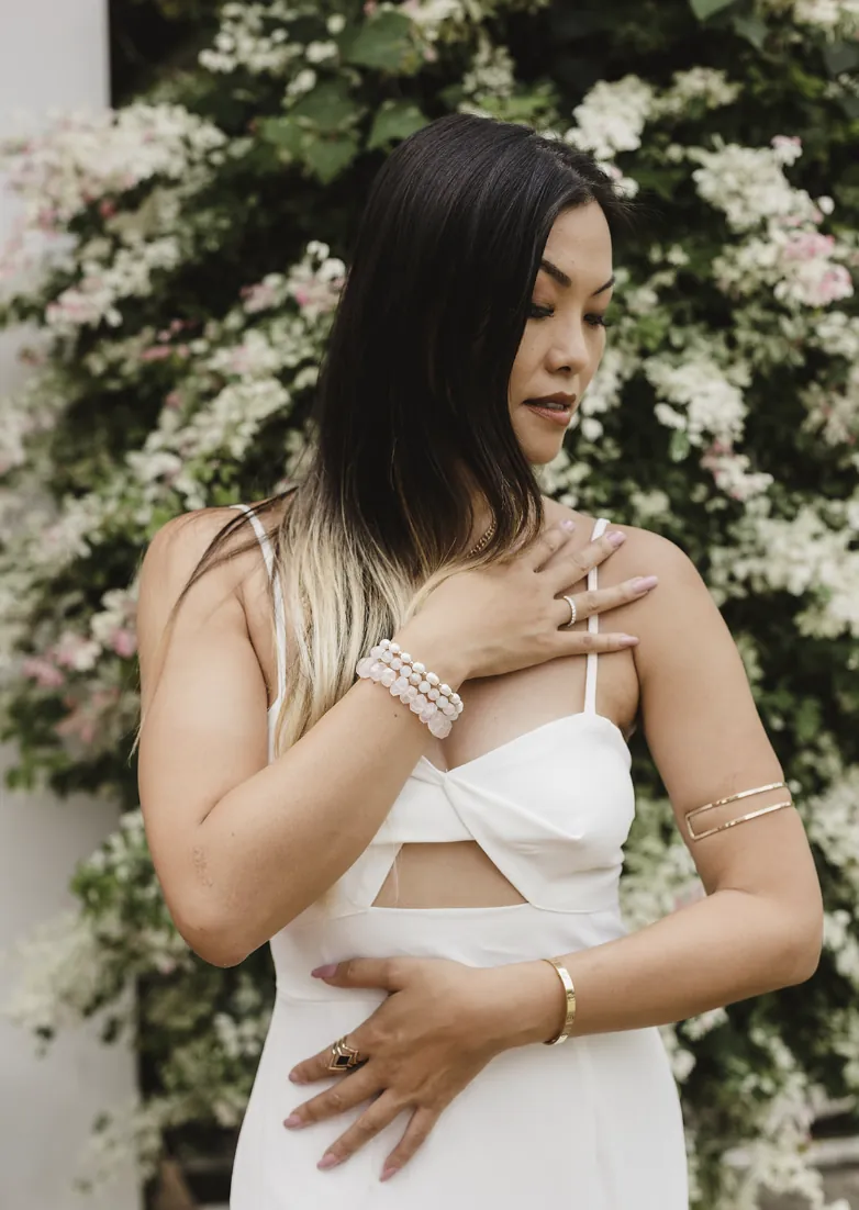Alice Muse standing among pale flowers with one hand over her heart